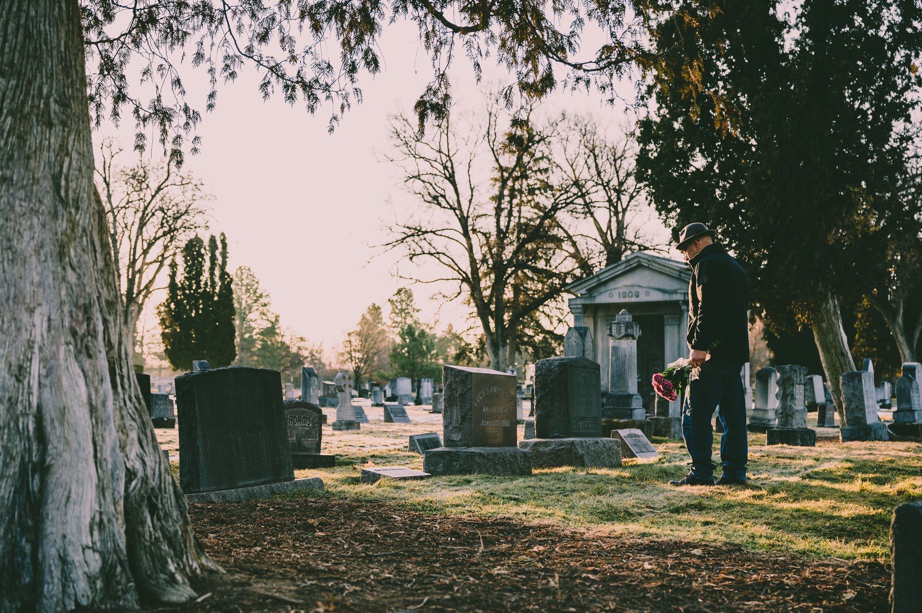 Man holding flowers in a cemetery at sunset